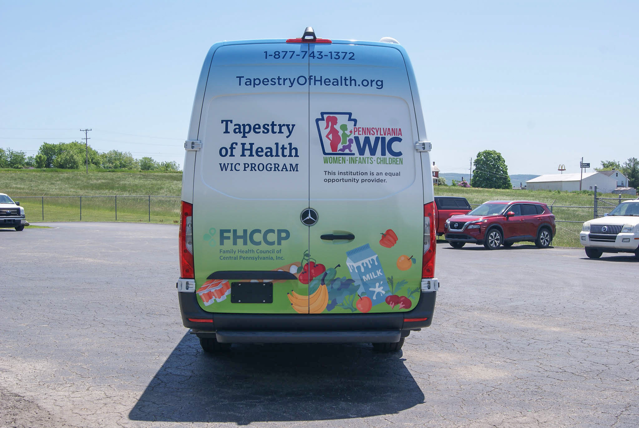 Direct view of the Mobile Outreach sprinter van's back doors and the decals. It features the Tapestry of Health's logo for the WIC program, their website, and their phone number.