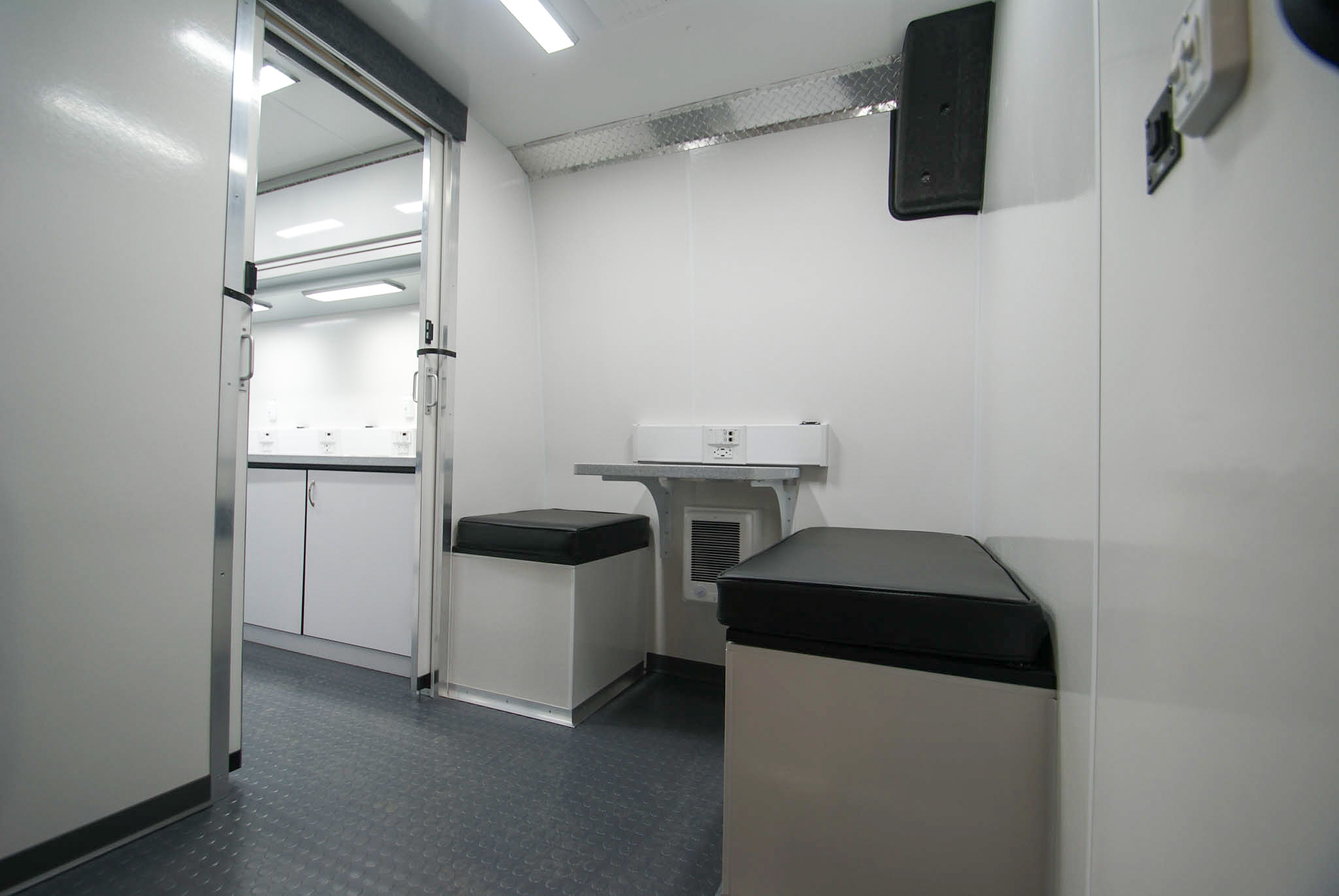 The front room of the Mobile Medical Exam sprinter as viewed from the front entrance. You can see the waiting area. The door to the back room is open, so you can also see the counters and sink.
