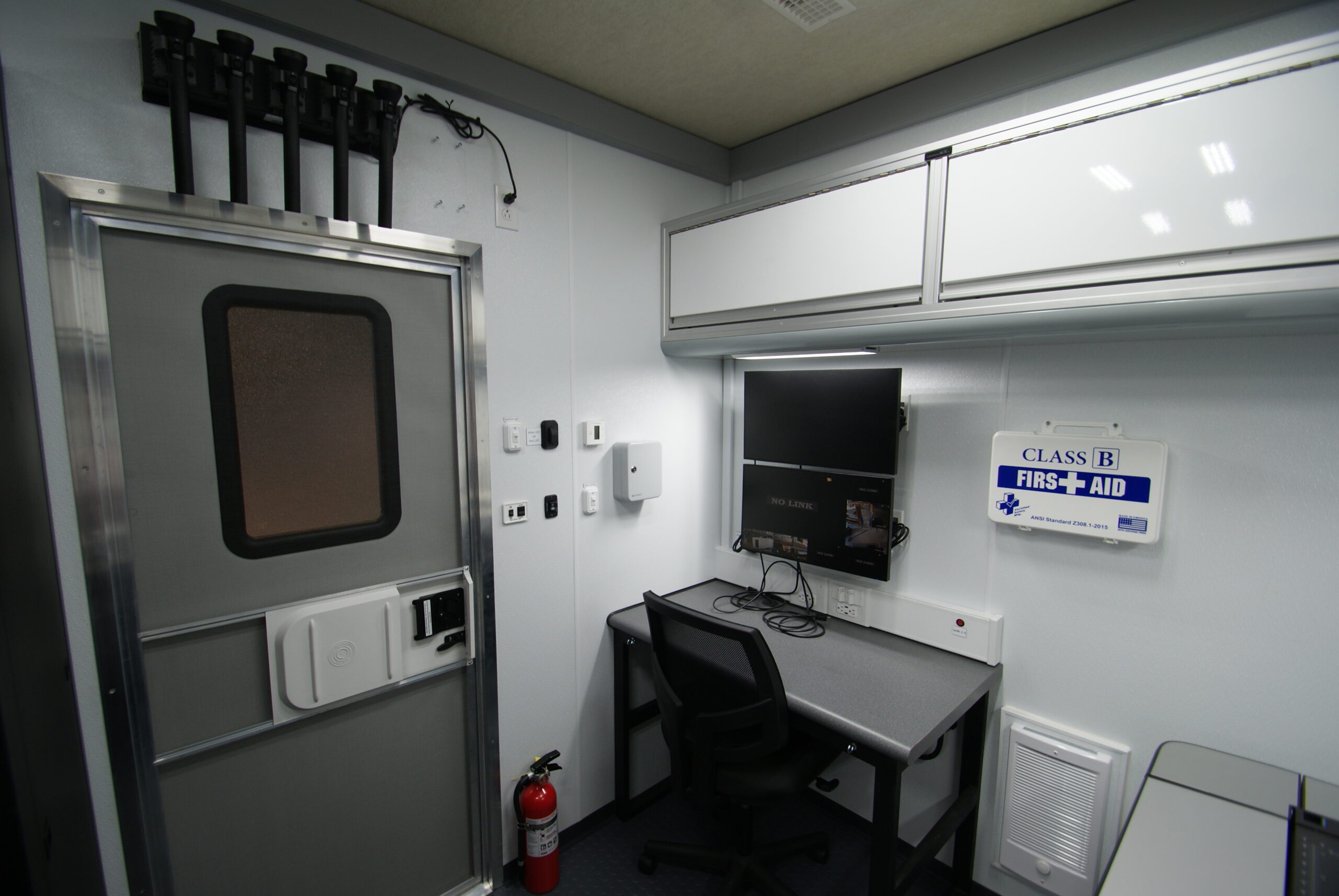 A view of a workstation, first aid kit, and overhead cabinets inside the unit for Westmoreland County Public Safety.