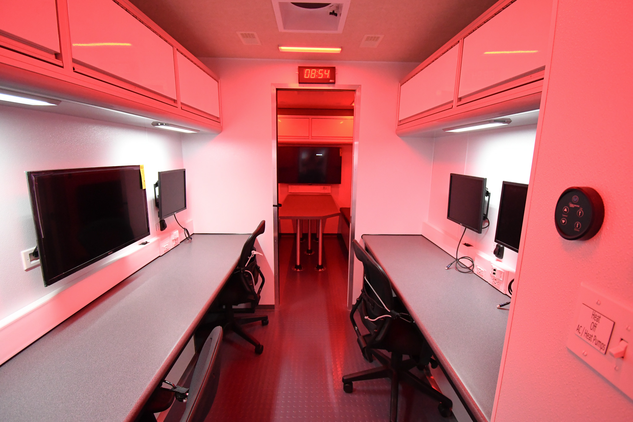 A view of three workstations inside the unit for Caribou, ME. The red LED lighting is on.